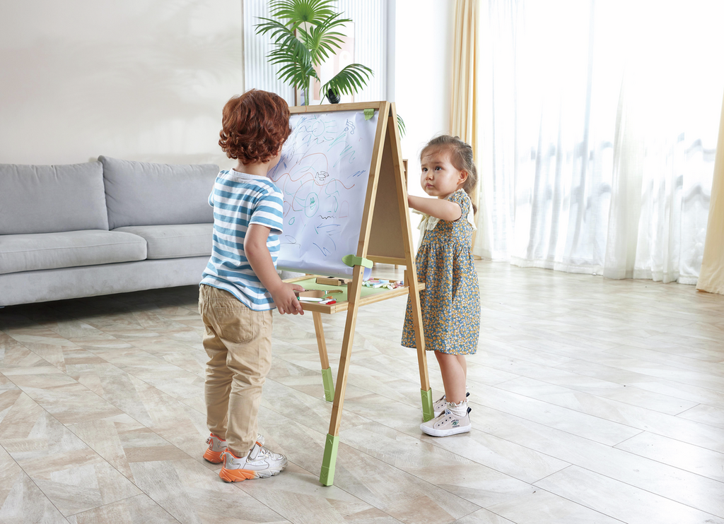 Niño dibujando en la pizarra del caballete Hape Step Up.