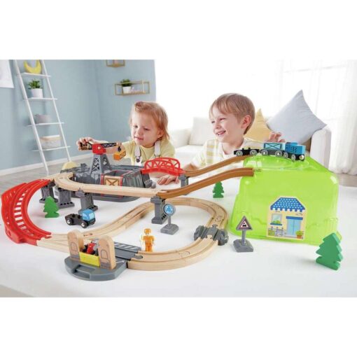 Niño construyendo el circuito del tren con bloques de Hape sobre la caja-escenario.