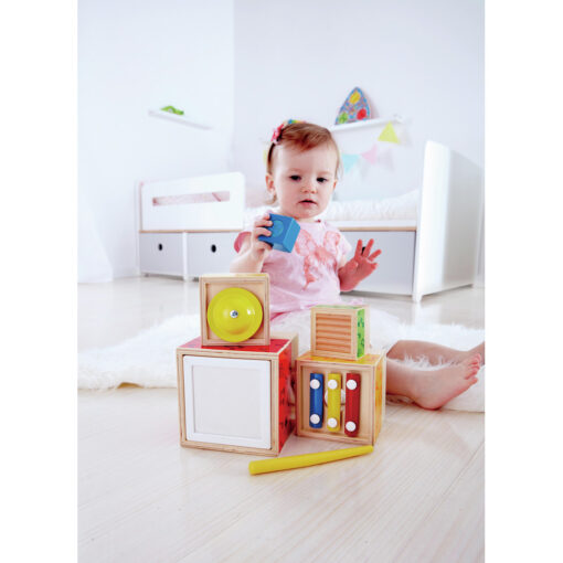 Bebé apilando los bloques musicales de Hape y escuchando el sonido.