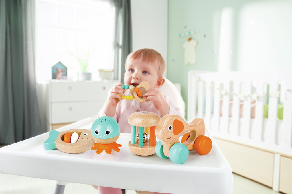 Bebé manipulando el sonajero pez del Set Sensorial Hape.
