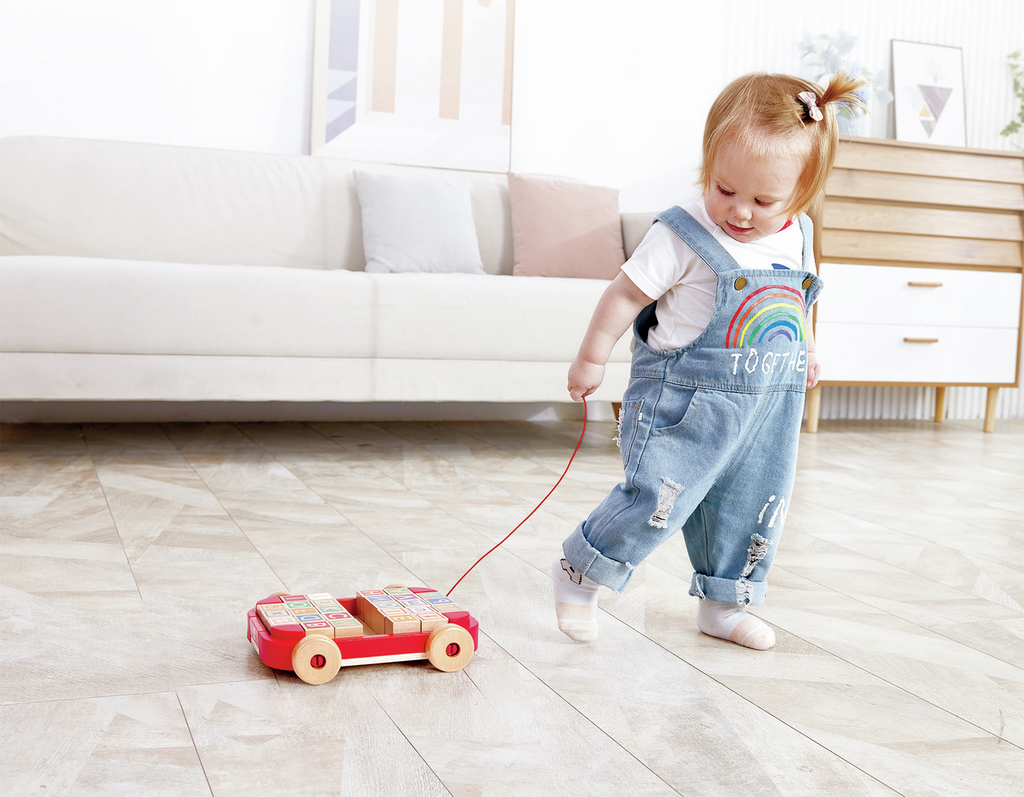 Niño arrastrando el carrito mientras juega con los bloques de letras.