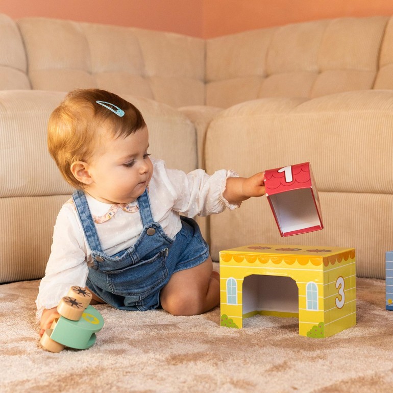 Bebé usando el sonajero de madera del set My First Toy Goula.