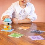 Niño jugando con el personaje electrónico Coco y las tarjetas de animales.